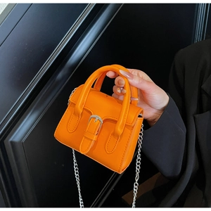Detail of orange mini handbag featuring silver buckle strap and metal chain shoulder strap