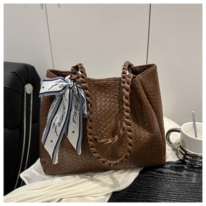 Close-up of brown woven tote bag with twisted handles and elegant Paris print silk scarf