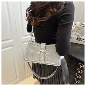 Close-up of grey pleated underarm bag with gold H-buckle worn on model shoulder