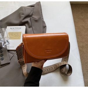 Detail of trendy orange small square bag with woven strap and fashion bags text