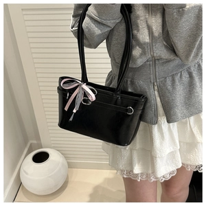 Détail du sac sous le bras en cuir verni noir avec nœud rose et boucle en métal argenté