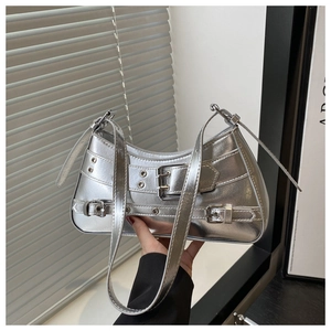 Detail view of silver metallic underarm bag with decorative belt straps and metal eyelets