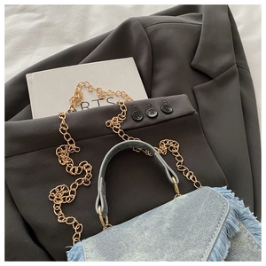 Detailed shot of denim fabric texture with fringe edges and gold metal chain strap