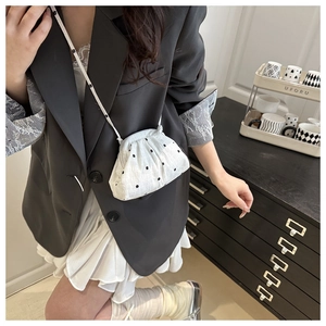 Mini white fabric cloud tote with black floral patterns worn by a model in casual style