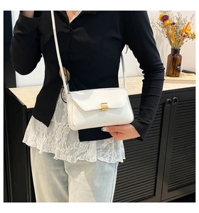 Detail of white baguette bag with golden square clasp and slim shoulder strap