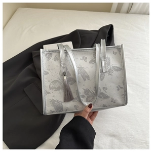 Detail of silver-grey butterfly jacquard tote bag with stylish tassel and slim handles