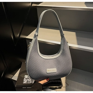 Close-up of blue-grey hobo bag featuring woven texture, side metal chain and brand logo