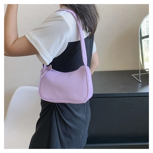 Close-up of a minimalist lavender nylon underarm baguette bag worn by a model