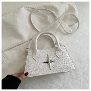 Close-up of white woven leather handbag with silver star detail and long strap