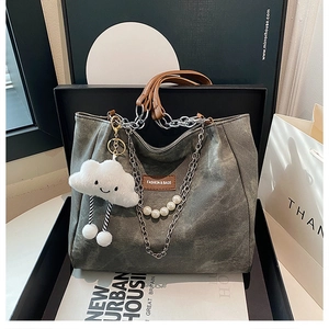 Detail of dark grey tote with metal chain, white pearls and cloud charm in a gift box