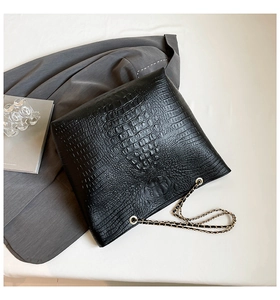 Close-up of black crocodile pattern faux leather texture and golden chain strap detail