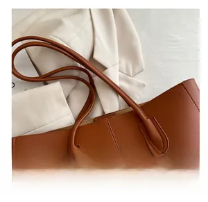 Close-up of brown faux leather tote bag showing slim handles and vertical stitching detail
