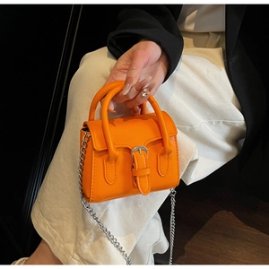 Close-up of vibrant orange mini square bag with silver chain strap and metal buckle