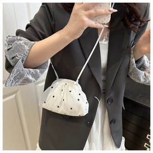 Close-up of white floral pattern puffy crossbody bag styled with a grey blazer