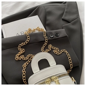 Detail der weißen Mini-Eimertasche mit Goldgriff und Doppel-Reißverschluss auf Blazer