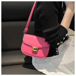 Detail of pink crossbody saddle bag with gold metal buckle shown on a female model