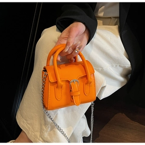 Detail of vibrant orange mini square bag with silver chain strap and decorative stitching