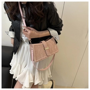 Detail view of pink textured leather bag with gold buckle and slim shoulder strap