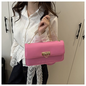 Detail of hot pink shoulder bag with golden twist lock and chain strap on hand