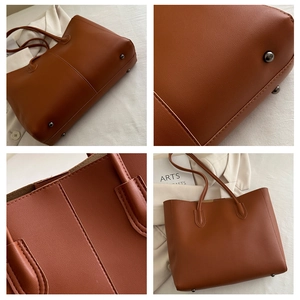 Detail view of large brown tote bag featuring pebbled leather texture and protective metal feet
