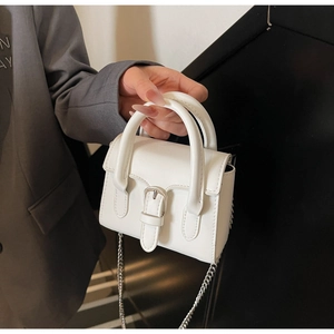 Detail of white leather mini handbag with silver buckle and delicate metal chain strap