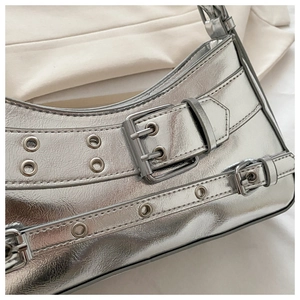 Detail of silver metallic shoulder bag with Y2K style metal eyelets and buckle texture