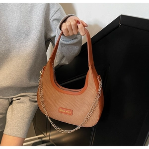 Detail of woven fabric and brown leather splicing on a stylish shoulder bag with gold chain