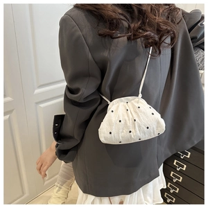Détail du mini sac cabas plissé à fleurs porté par le mannequin pour l'échelle