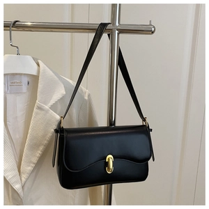 Detail of elegant black matte leather bag featuring a polished gold capsule twist lock