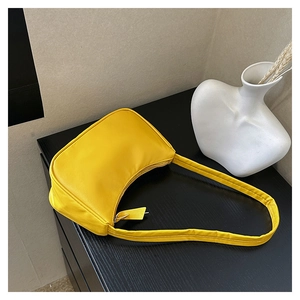 Detailed close-up of bright yellow nylon crescent shoulder bag on a dark texture