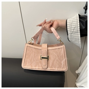 Detail view of pink baguette bag with unique ruched texture and gold metal buckle strap