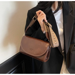 Detailed view of brown oil leather crossbody bag with ethnic patterned wide strap