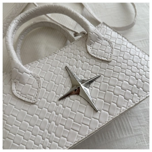 Macro shot of white woven texture handbag featuring a silver star metal hardware detail