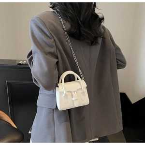 Rear view of a model wearing a white mini crossbody bag with silver chain strap