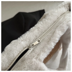 Detailed close-up of the silver metal zipper and soft white plush texture of the tote bag