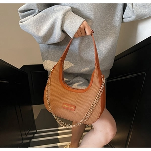 Detail of woven hobo bag featuring smooth leather trim and decorative gold chain