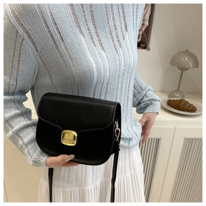 Détail d'un sac besace noir avec finition mate et fermoir métallique carré doré