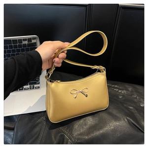 Close-up of champagne gold polished handbag with a decorative metal bow clasp and zipper