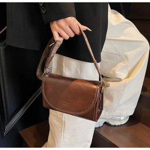 Close-up of retro brown oil leather crossbody bag featuring white stitching and logo