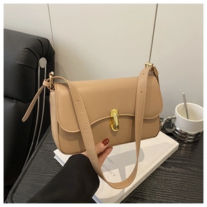 Close-up of stylish beige crossbody bag featuring an elegant oval gold metal twist lock