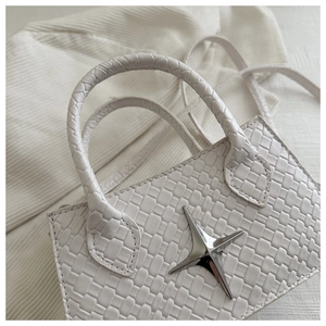 Close-up of white woven leather handbag featuring a silver star-shaped metal buckle detail