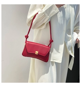 Detail of red baguette bag with gold square buckle and unique knotted leather strap