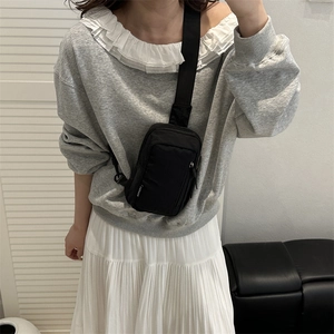 Minimalist black nylon crossbody chest bag with adjustable strap worn by female model
