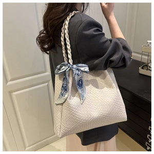 Detail of white woven tote bag featuring a checkered texture and elegant printed scarf accessory