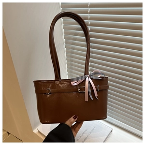 Détail du sac à épaule en cuir verni marron brillant avec nœud décoratif et boucle en métal
