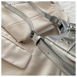 Detail of silver metallic leather shoulder bag with punk eyelet studs and buckle strap