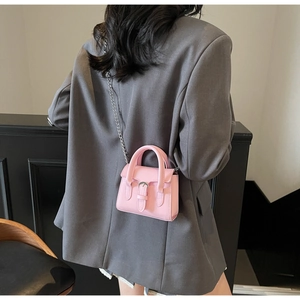 Détail du mini sac à main rose en cuir mat avec boucle argentée porté par un mannequin