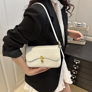 Elegant cream white flap shoulder bag with gold clasp shown on a model in a suit