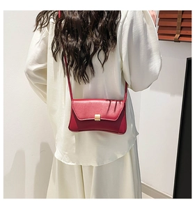 Detail of wine red leather shoulder bag featuring a sleek rectangular gold metal clasp