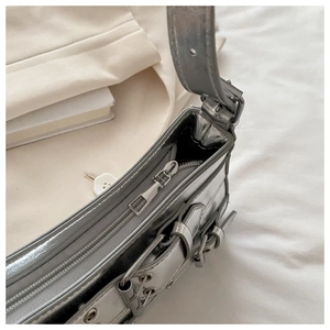 Close-up of silver textured leather shoulder bag with metallic eyelets and zipper detail